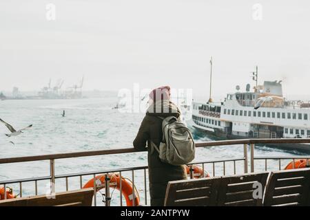 Uno studente o un turista ragazza è in piedi sul ponte o su una barca a vela su un traghetto lungo il Bosforo a Istanbul e gode di splendide viste. Foto Stock