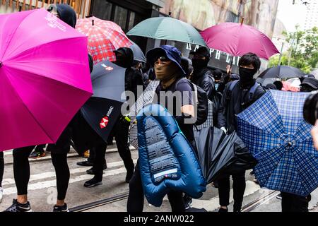 Manifestanti proteggersi con ombrelloni durante il rally.inserendo l'ottavo mese di disordini civili, i dimostranti si sono riuniti presso un anti-rally comunista, per protestare contro il Partito comunista cinese. Manifestanti hanno ascoltato discorsi, sventolate le bandiere e slogan cantati. Più tardi, la polizia in tenuta da sommossa apparve e sparato gas lacrimogeni, arrestando diversi manifestanti. Foto Stock