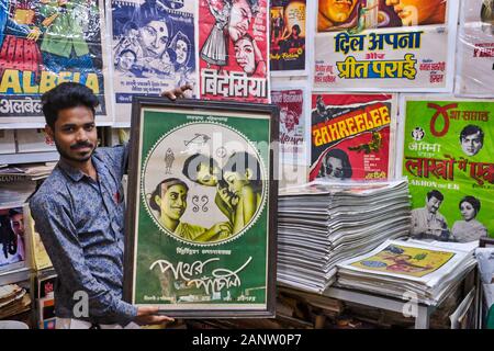 Kaleem Khan, co-proprietario del negozio Poster Stuff in Chor Bazar (Thieves' Market), Mumbai, India, tenendo un poster originale del film Pather Panchali Foto Stock