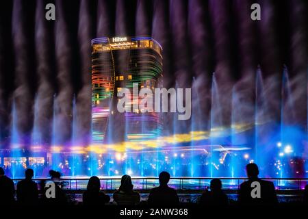 Tashkent, Uzbekistan - 30 Ottobre, 2019: guardare la gente ballare fontana illuminata di notte nella nuova città di Tashkent Park Foto Stock