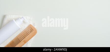 La perdita di capelli di concetto di trattamento. Appartamento Chiara laici bottiglia di shampoo, bambù Pettine capelli e asciugamani su sfondo verde. Banner mockup con cura dei capelli cosmetic prod Foto Stock