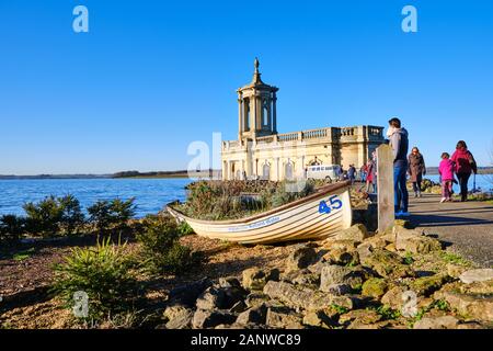 St Matthews Chiesa Normanton Rutland acqua su una giornata soleggiata con un Anglian acqua barca a remi in primo piano e un vibrante blu cielo Foto Stock