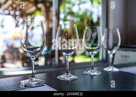 Affiancate varie dimensioni di vino bicchieri vuoti in un ristorante tavola messa a fuoco selettiva view, coppe per bere e degustare vini, sala degustazione stemware Foto Stock