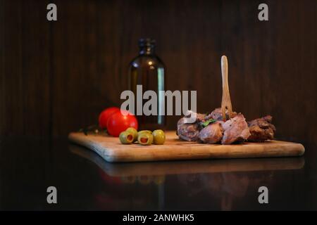 Carne di anatra con pomodori e olive su una tavola di legno. Materie rustico che serve cibo al ristorante. Gourmet di piatti gustosi e concetto di cucina a vista Foto Stock