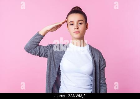 Yes Sir! Ritratto di obbediente brunette ragazza adolescente con bun hairstyle in abiti casual dando ascolto salutano per ordinare con gravi responsabilità exp Foto Stock