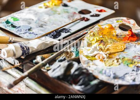Tavolozza con un mix di colori pennelli e colori di close-up Foto Stock