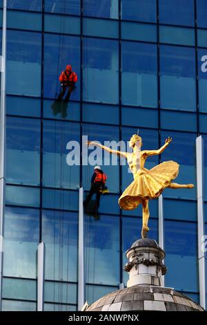 Statua della ballerina russa Anna Pavlova sulla sommità della cupola di Victoria Palace Theatre e dei lavoratori sul vetro frontale Building, Victoria, London, Regno Unito Foto Stock