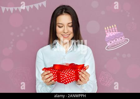 Freestyle. Giovane donna in piedi isolato su grigio con presente sorridente allegro Foto Stock
