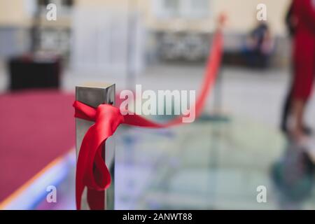 Processo di taglio il nastro rosso durante l'inaugurazione del nuovo centro commerciale Mall building, apertura della mostra, vista ravvicinata di ribbo rosso Foto Stock