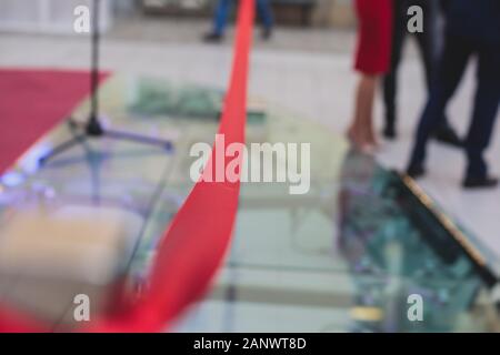 Processo di taglio il nastro rosso durante l'inaugurazione del nuovo centro commerciale Mall building, apertura della mostra, vista ravvicinata di ribbo rosso Foto Stock