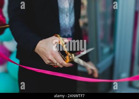 Processo di taglio il nastro rosso durante l'inaugurazione del nuovo centro commerciale Mall building, apertura della mostra, vista ravvicinata di ribbo rosso Foto Stock