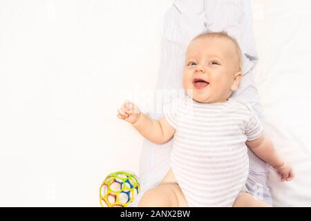 Felice piccolo bambino giaceva sul letto sorridere e ridere balbettio Foto Stock