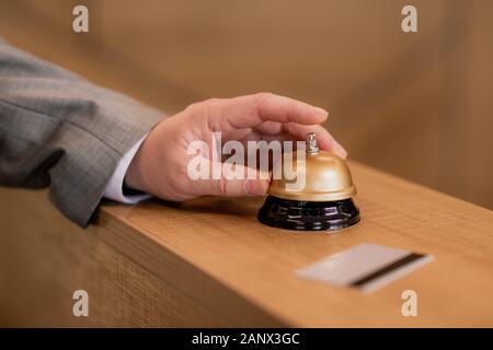 Mano di viaggia per lavoro anello di spinta pulsante sul banco della reception in legno Foto Stock