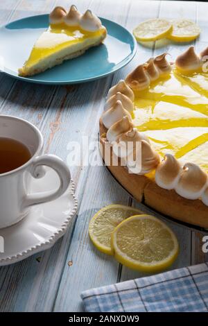 Torta al limone su una tavola di legno tavolo blu. La colazione vicino alla finestra Foto Stock