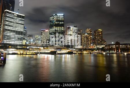 Il traghetto di Circular Quay attracca di fronte al quartiere centrale degli affari di notte a Sydney, Australia Foto Stock