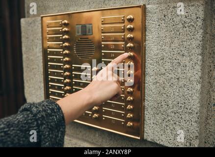 Femmina lato preme il pulsante Interfono per accedere all'interno. Foto Stock