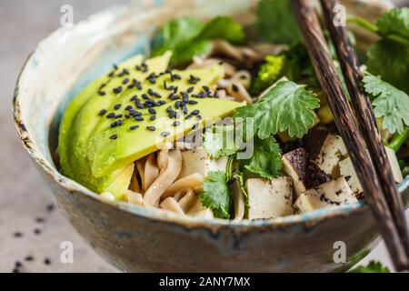 Tagliatelle di grano saraceno soba con tofu, broccoli, avocado, piantine e coriandolo. Sano cibo vegan concetto. Foto Stock