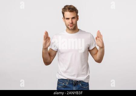 Bella bionda elegante barbuto uomo macho in t-shirt bianco, alzando le mani vicino al petto come se tiene qualcosa, introdurre il logo aziendale, banner o Foto Stock