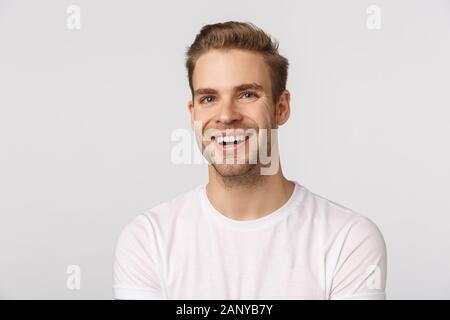 Trasognata affascinante bionda caucasian ragazzo con gli occhi blu e setole, ridendo e sorridendo dalla gioia e delizia, esprimere emozioni positive, cercare Foto Stock