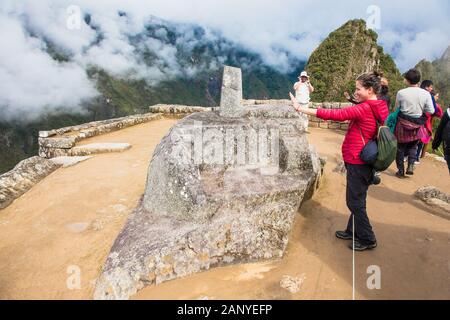 Machu Picchu Pueblo, Perù - Jan 8, 2019:turista nella parte anteriore della pietra Intihuatana, dettaglio dal peruviano città inca, sito patrimonio mondiale dell'unesco, sacro va Foto Stock