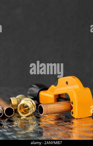 Tubo di rame e fresa con connettori idraulici su un acciaio checker superficie di lastra. Strumento di tubazioni e pezzi di ricambio Foto Stock