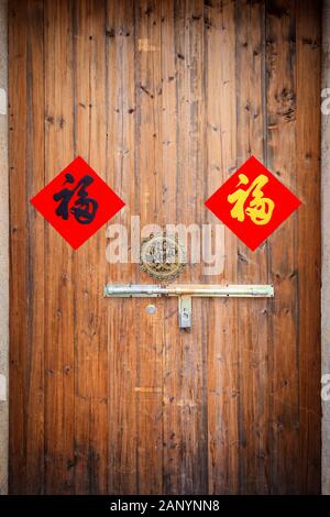 Due coloratissimi benedizione Cinese 'FU' sulla tradizionale cinese porta in legno con maniglia e lucchetto. Il 'FU' con sfondo rosso, fortuna e felicità Foto Stock