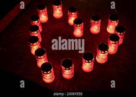 Cuore della candela rossa si illumina di notte in un cimitero. Foto Stock