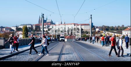 Praga, Repubblica Ceca - 14 ottobre 2018: i turisti a piedi dal Ponte Manes oltre il Fiume Vlatva e il Castello di Praga in background, highlig Foto Stock