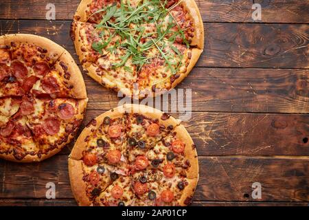 Composizione di tre diversi tipi di pizze sul tavolo di legno Foto Stock