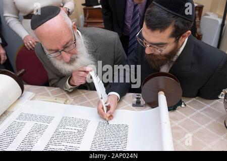 Il completamento della scrittura di una nuova Torah è un processo comune dove congregants, assistito da un graffietto, compilare una lettera. In Bayside, Queens, NYC. Foto Stock