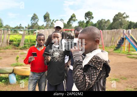 Una giovane ragazza ugandese dell'Africa Orientale tiene una macchina fotografica istante mentre impara la fotografia nella campagna rurale Foto Stock