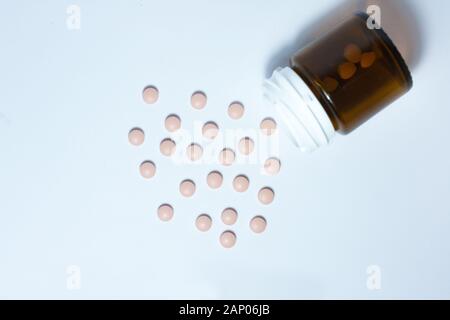 Rosa medical pillole e compresse di fuoriuscita di un flacone di farmaco su uno sfondo bianco, vista dall'alto con copia spazio per testo, cura di salute mi farmaceutica Foto Stock