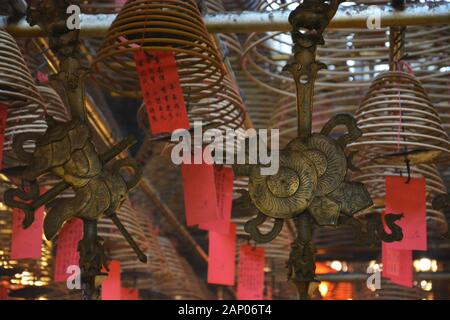 Personale in ottone decorato di fronte alle bobine di incenso al Tempio Man Mo di Hong Kong. Foto Stock