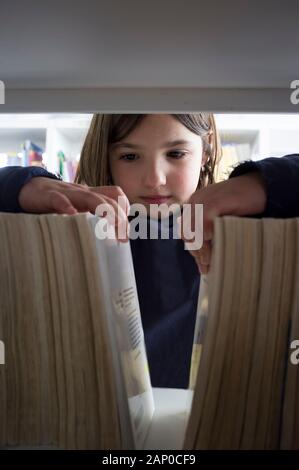 Ragazza giovane selezione di libri dalla biblioteca scaffale. I bambini la creatività e la fantasia del concetto. Foto Stock