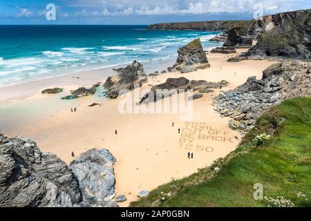 Un messaggio di avvertimento scritto nella sabbia sulla spiaggia di Bedruthan Steps sulla North Cornwall Coast. Foto Stock