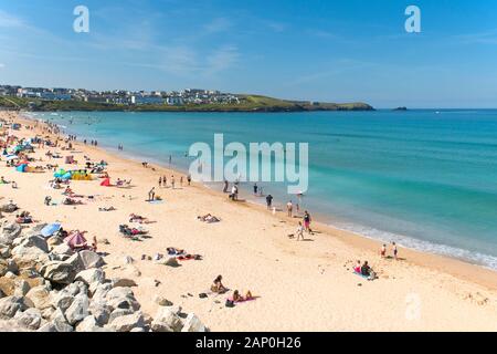 Turisti di rilassarsi e godersi il sole estivo come essi prendere il sole sulla spiaggia di Fistral a Newquay in Cornovaglia. Foto Stock