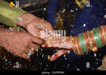 Primo piano su indiano sposo che mette l'anello sulla sposa indiana Foto Stock