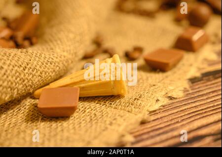 Torta in un cono di cialda, cioccolato e chicchi di caffè su uno sfondo di homespun ruvida stoffa. Close up Foto Stock