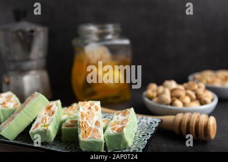 Torrone di organico a base di miele, pistacchi, nocciole, mandorle e i dadi su un rustico sfondo scuro. Foto Stock