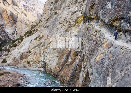 Trekking su un sentiero stretto attraverso una gola sul Sentiero Inferiore del Dampo in Nepal Foto Stock