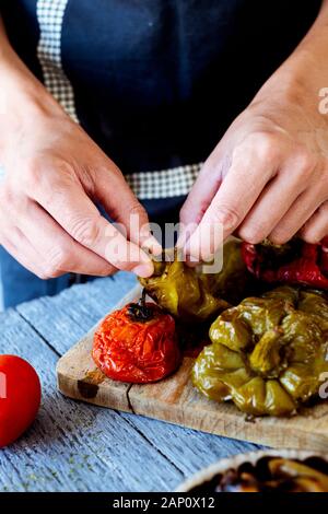 Primo piano di un uomo peeling alcune verdure grigliate, come peperoni rossi, peperoni verdi, pomodoro e cipolla, per preparare escalivada, un piatto tipico di Catal Foto Stock