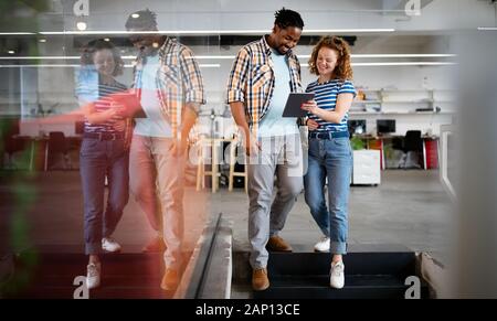 I colleghi discutere di affari e sorridenti mentre si cammina attraverso il corridoio di office Foto Stock