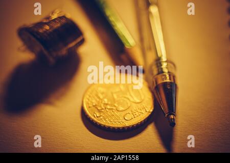 Golden 50 euro cent, pila di monete cmetal, penna e matita su carta tabella. Foto Stock