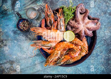 Vista superiore della grande lastra con i gamberi alla griglia e tentacoli di polpo decorato con verde Foto Stock