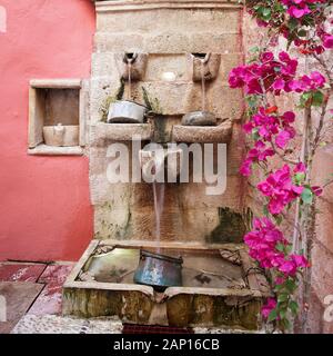 Un delizioso cortile caratteristica fontana, catturato in una stradina ristorante nel cortile a Rethymnon, Creta. Foto Stock