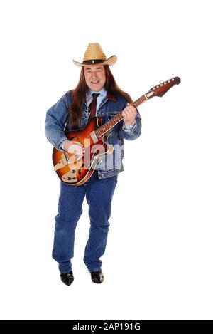 Un bel uomo indigeni in un paio di jeans giacca, pantaloni e un cappello da cowboy standing e suonare la chitarra, isolato per sfondo bianco Foto Stock