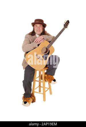 Un Medioevo uomo indigeni in scarpe di fantasia seduto e tenendo la sua chitarra in una camicia e hat, isolato per sfondo bianco Foto Stock