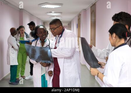 Gli studenti di medicina, stagisti. I giovani medici, razza mista, nel corridoio di un ospedale, consultazione. Immagini a raggi X di pazienti sono esaminati, medici pr Foto Stock