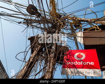 Caos cavo nella fornitura di energia elettrica e un segno Vodafone Foto Stock