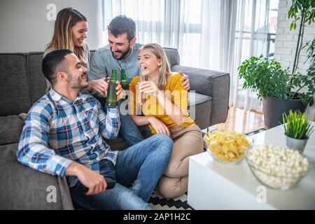 Gruppo di amici che godono di calcio su TV.They stanno emotivamente guardando il gioco nel soggiorno. Foto Stock